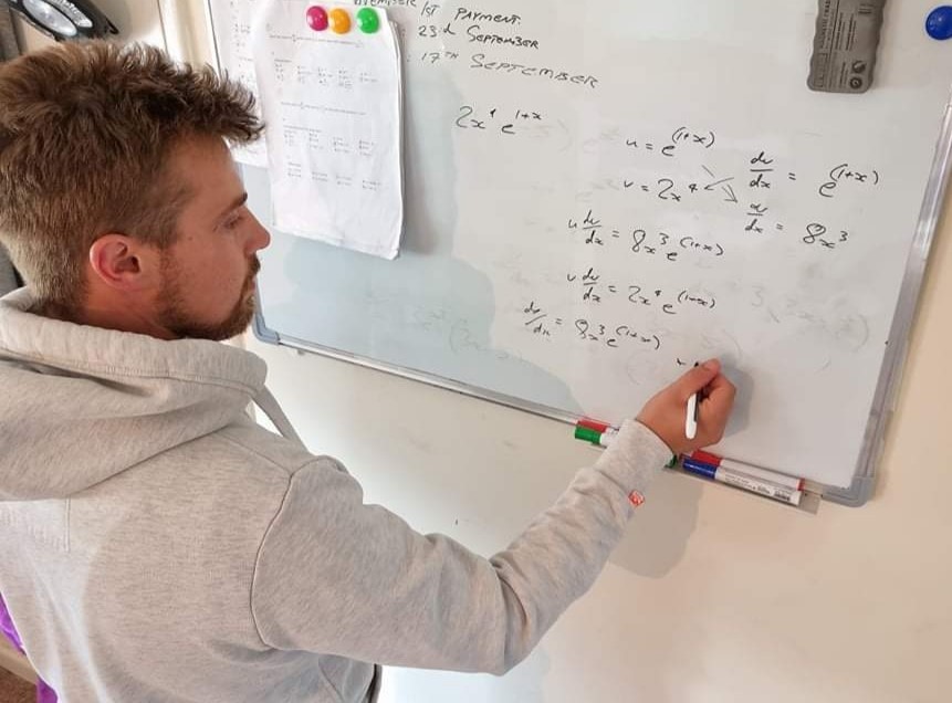 Student writing mathematics formula on a whiteboard